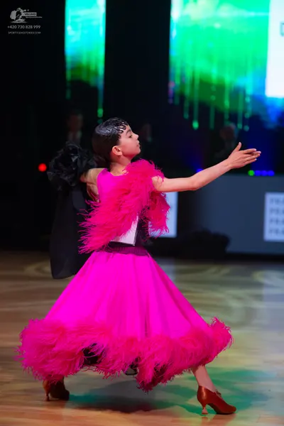 Dancesport competitor: Female dancer: bright pink ballroom dress with voluminous feather-like trim arou