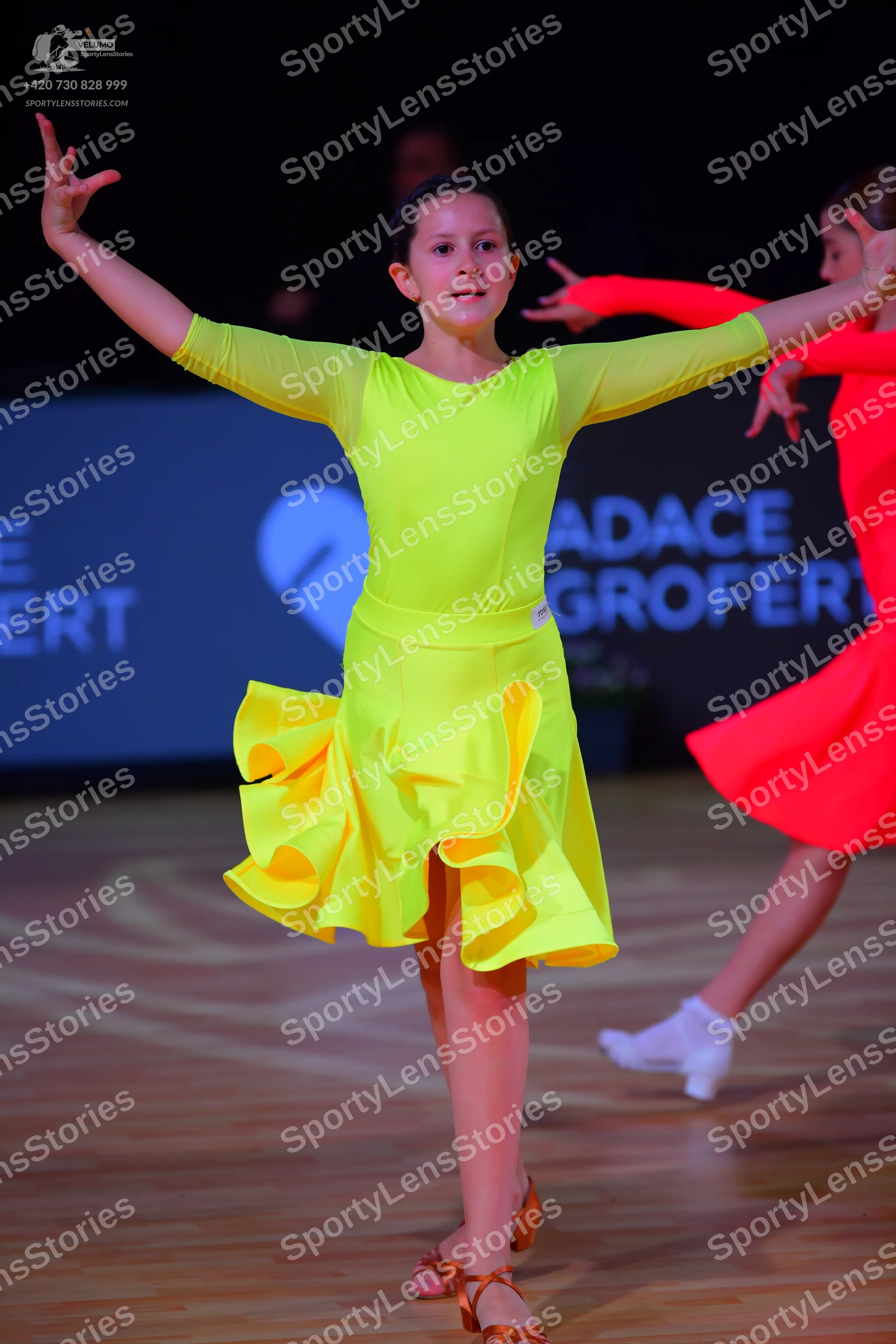 Dancesport competitor: Female dancer: neon yellow long-sleeved Latin dance dress with a ruffled skirt