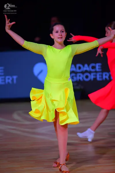 Dancesport competitor: Female dancer: neon yellow long-sleeved Latin dance dress with a ruffled skirt