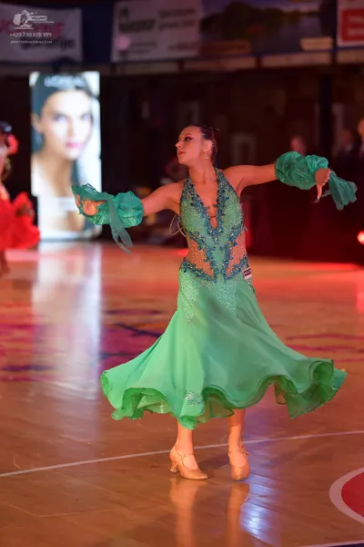 Dancesport competitor: Female dancer: green Latin dress with a sequined bodice and a flowing skirt with