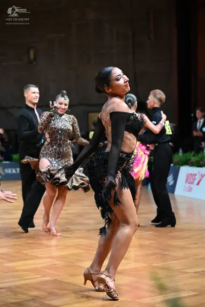 Dancesport competitor: Female dancer in foreground: black latin dress with fringe and long black gloves