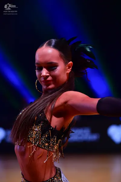 Dancesport competitor: Female dancer: black Latin-style top embellished with gold and clear sequins and
