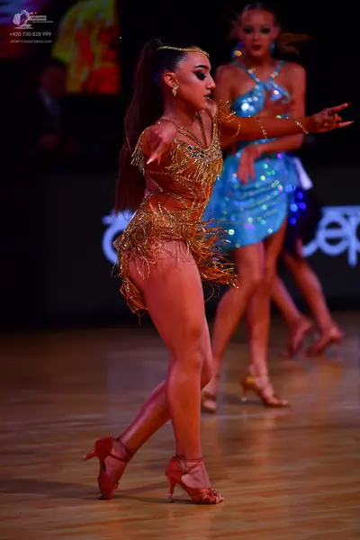 Dancesport competitor: Female dancer 1: gold/bronze latin dance costume with sequins, intricate beadwor