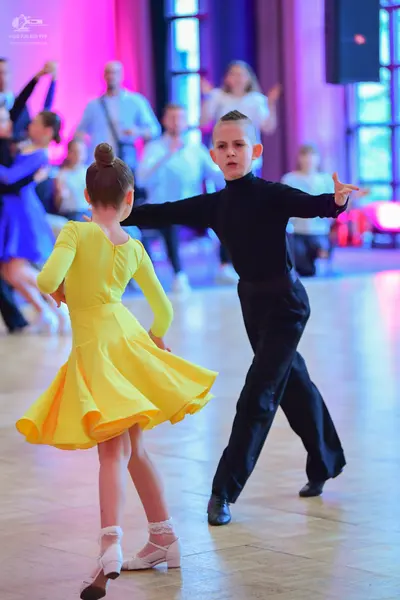 Dancesport competitor: Female dancer: yellow long-sleeved latin dress with a flared skirt and white dan