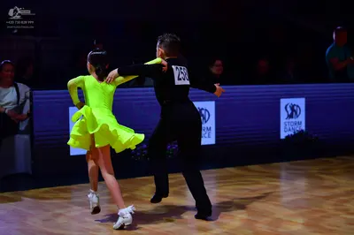Dancesport competitor: Female dancer: lime green long-sleeved latin dance dress with a flared skirt