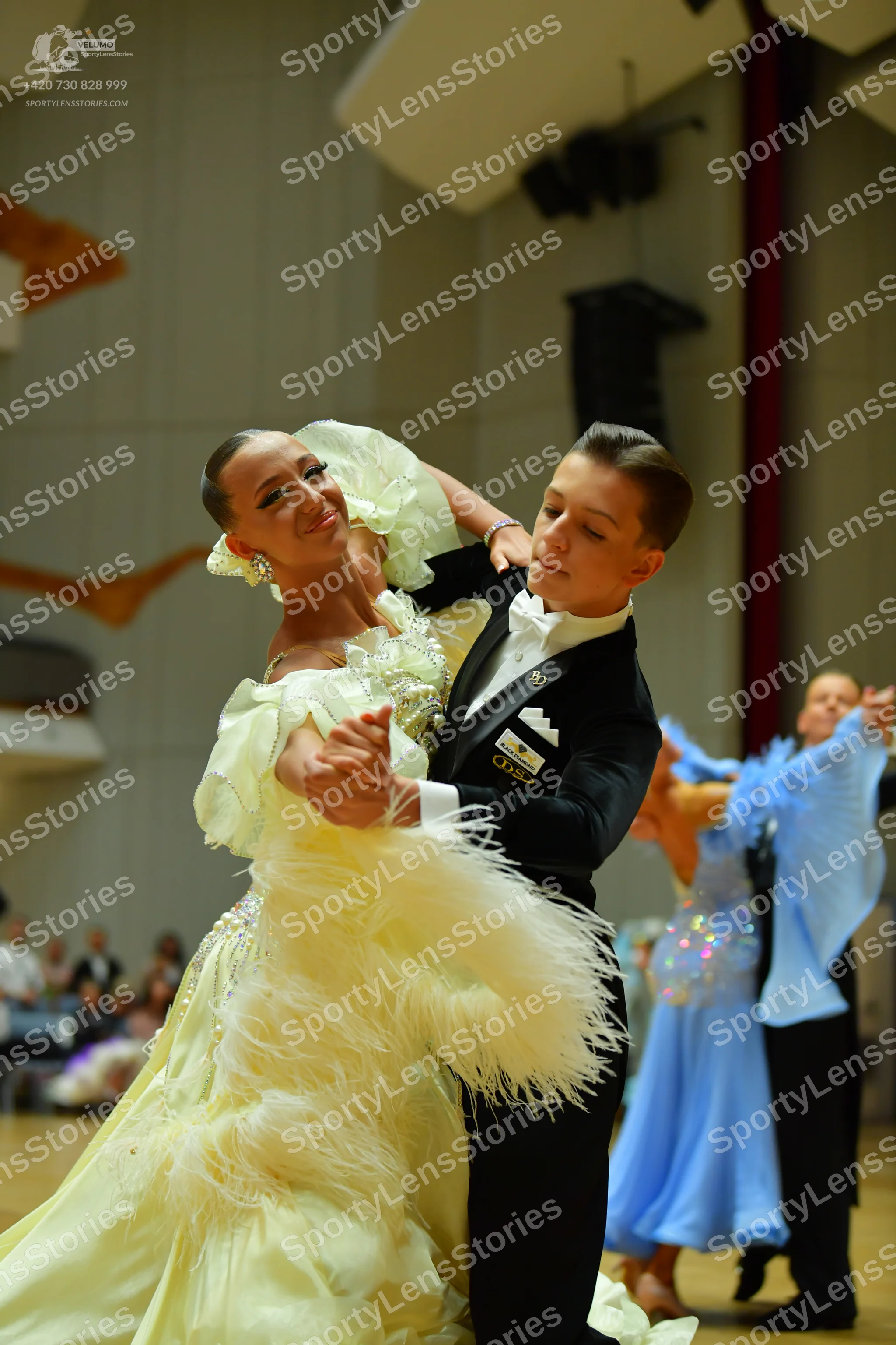 Dancesport competitor: Main female dancer: pale yellow ballgown with voluminous feather-like fringe and