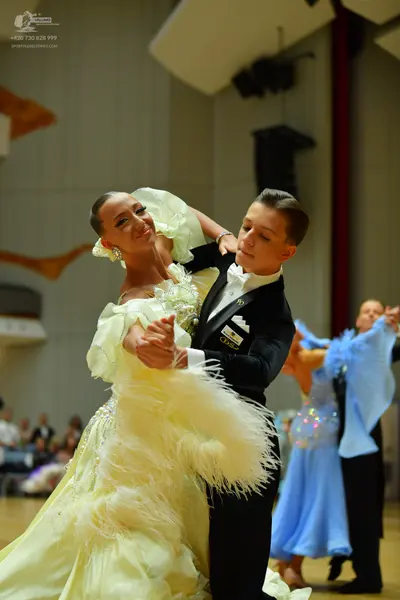 Dancesport competitor: Main female dancer: pale yellow ballgown with voluminous feather-like fringe and