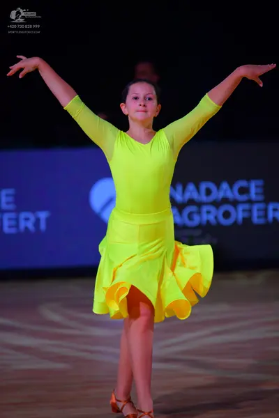 Dancesport competitor: Female dancer: bright yellow long-sleeved Latin dress with a flared, ruffled ski