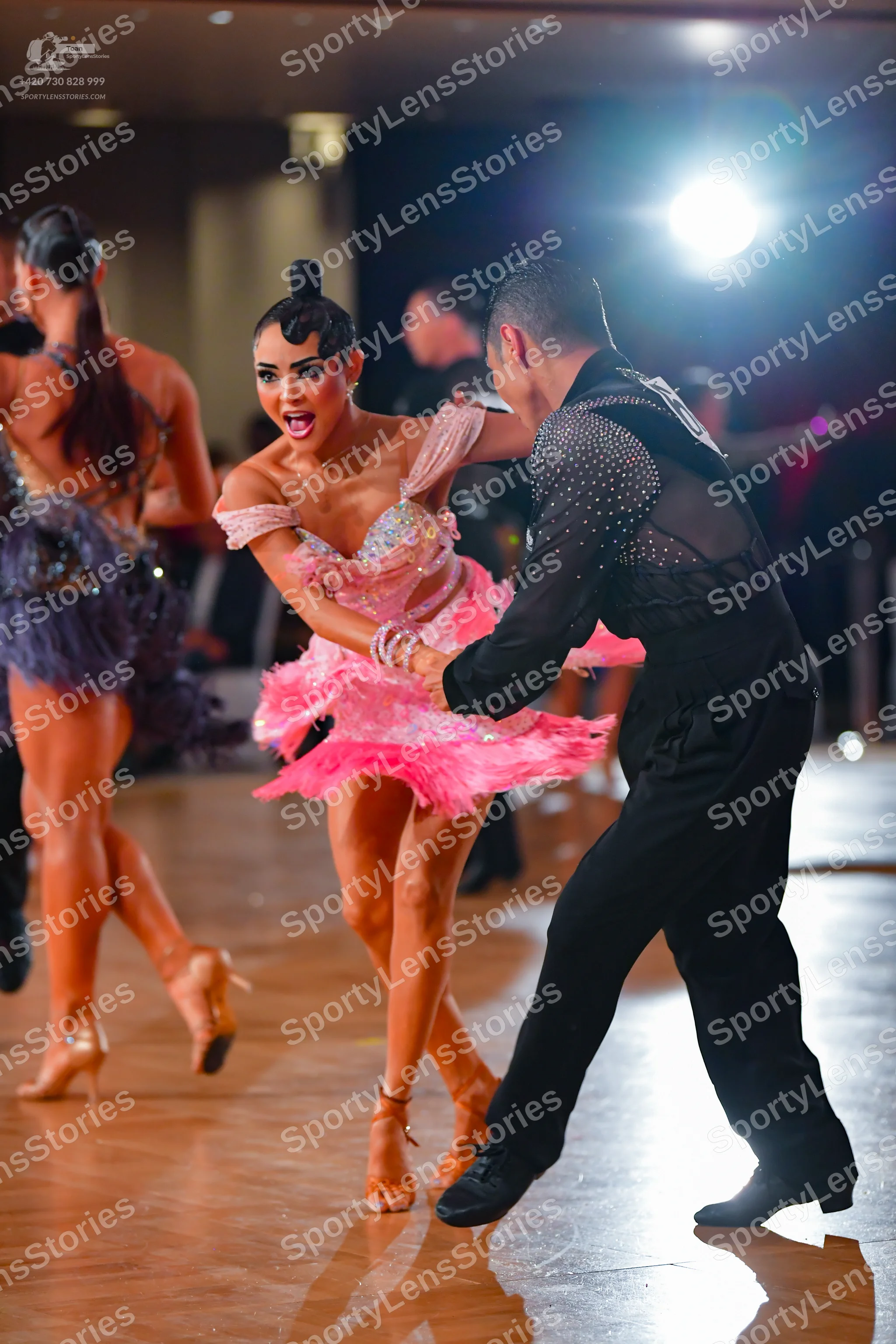Dancesport competitor: Female dancer 1: pink sequined Latin dress with an off-the-shoulder design and a