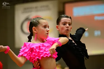 Dancesport competitor: Female dancer: bright pink ruffled latin dance dress with pink beaded bracelets 