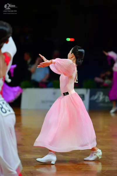 Dancesport competitor: Female dancer: white dress with pink accents