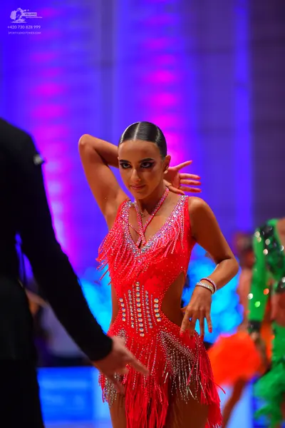 Dancesport competitor: Female dancer: red Latin dress with rhinestones and long fringe