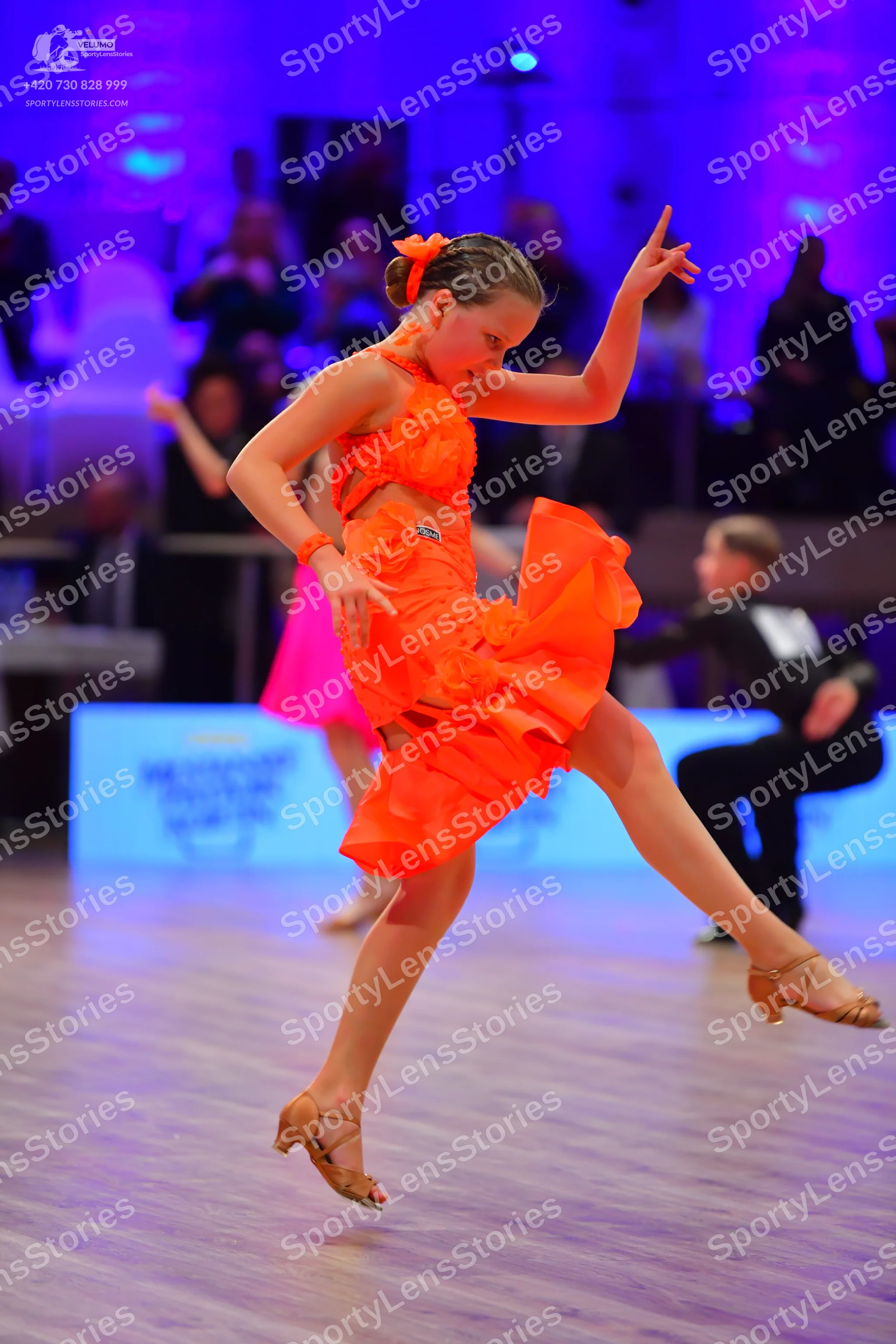 Dancesport competitor: Female dancer: orange Latin dance dress with a ruffled skirt and halter neckline