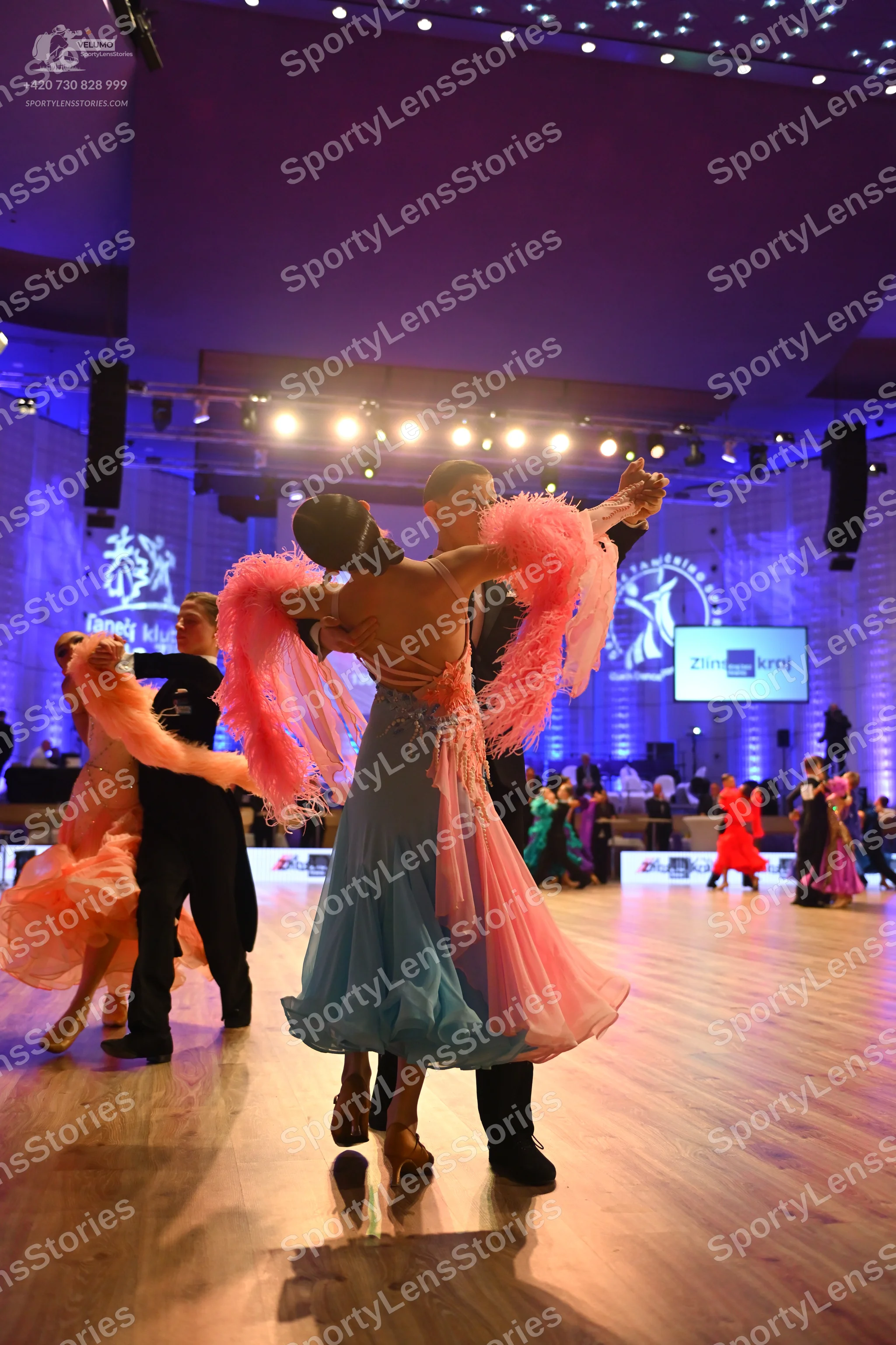Dancesport competitor: Main female dancer: light blue latin dress with large pink/peach feathered or fr