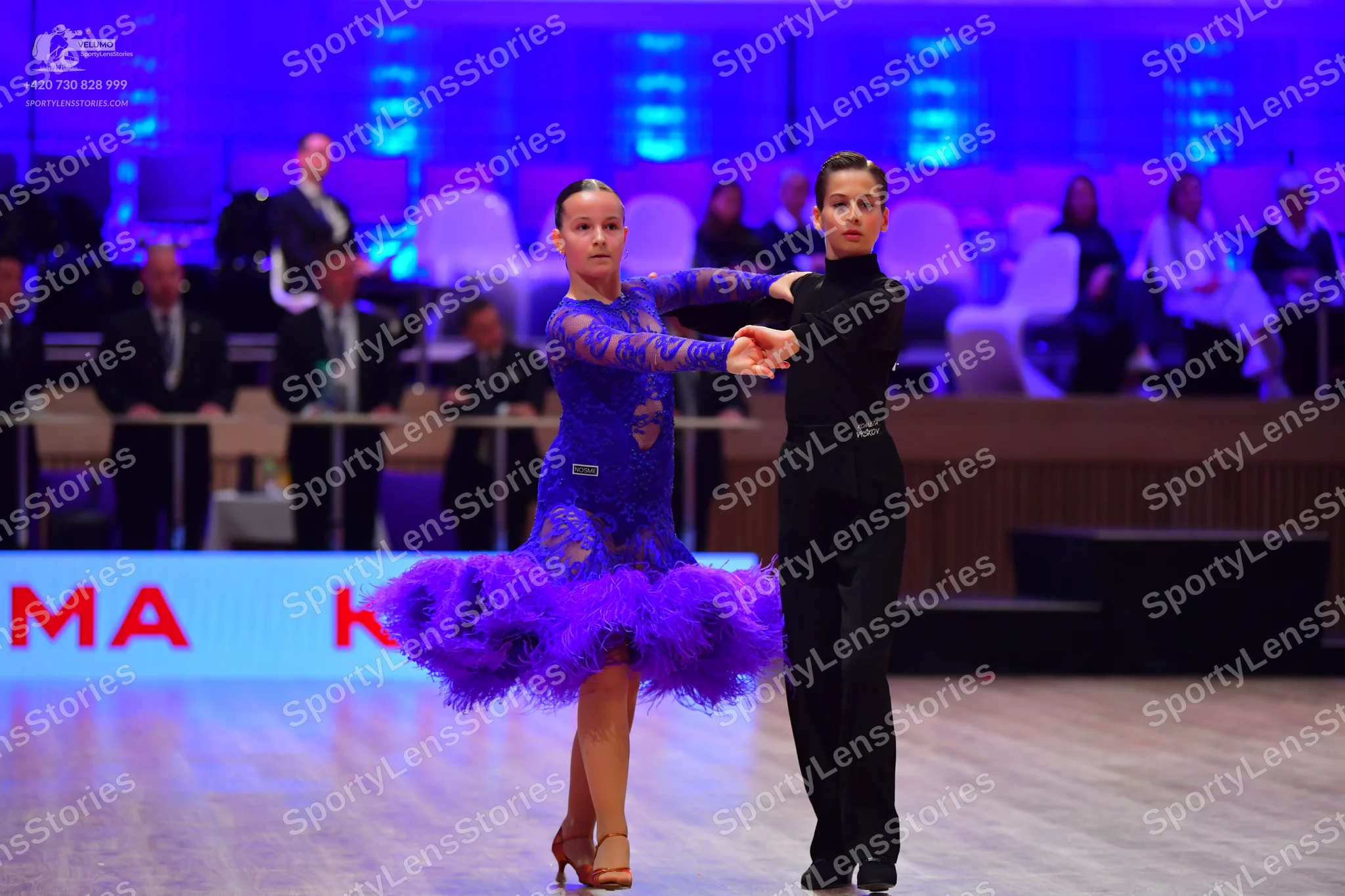 Dancesport competitor: Female dancer: blue Latin dance dress with patterned bodice and long sleeves, fe