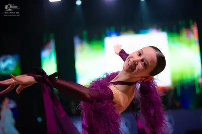 Dancesport competitor: Female dancer: purple Latin dress with purple feather trim and satin-like purple