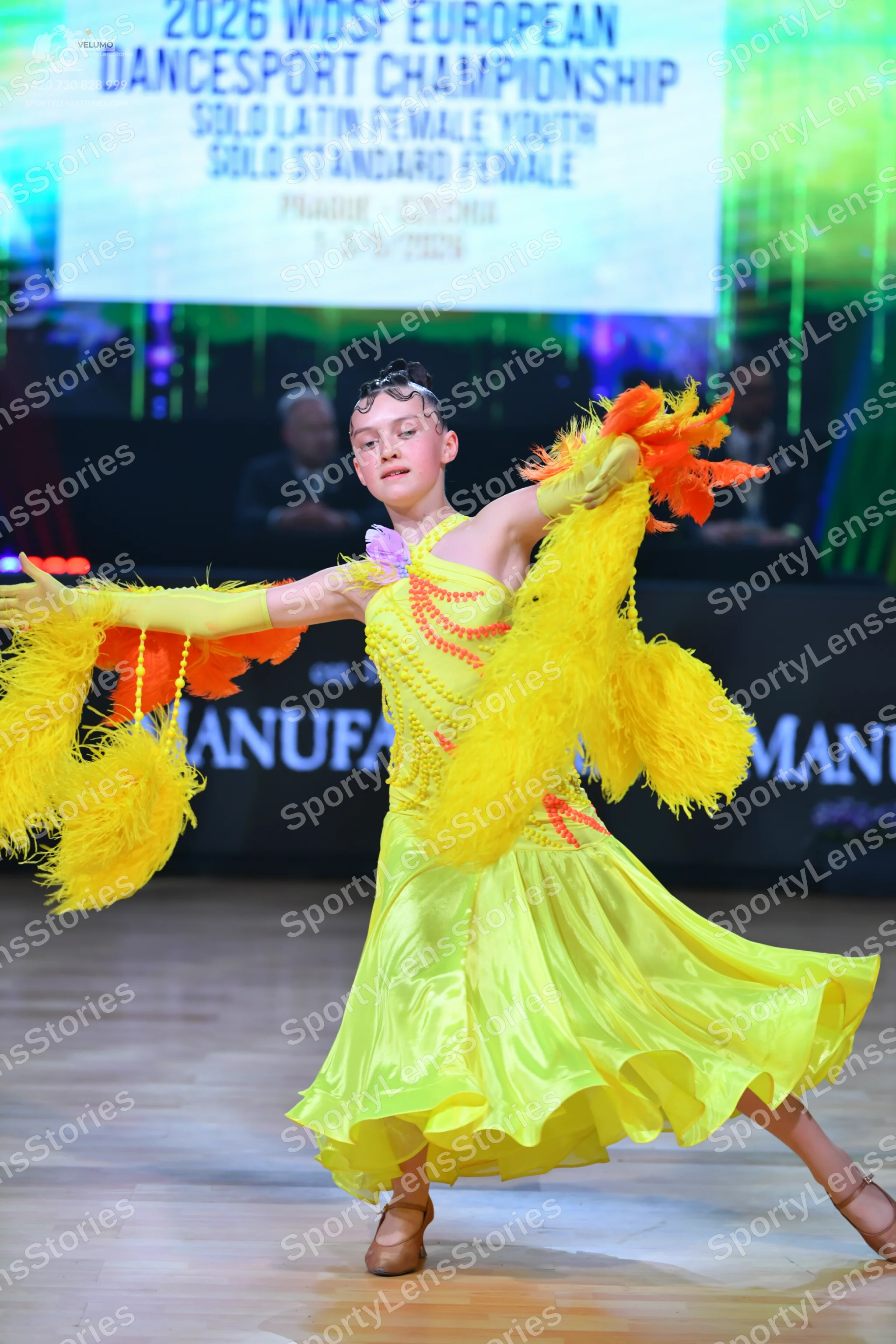 Dancesport competitor: Female dancer: yellow Latin dress with fringe, yellow gloves, and tan dance shoe