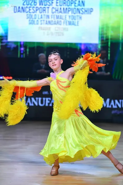 Dancesport competitor: Female dancer: yellow Latin dress with fringe, yellow gloves, and tan dance shoe