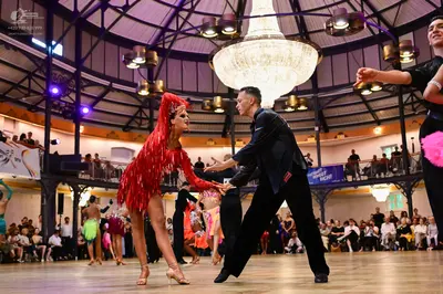 Dancesport competitor: Female dancer in foreground: red Latin dress with fringe
