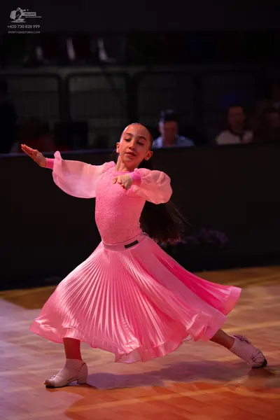 Dancesport competitor: Female dancer: bright pink long-sleeved ballroom dress with a full pleated skirt