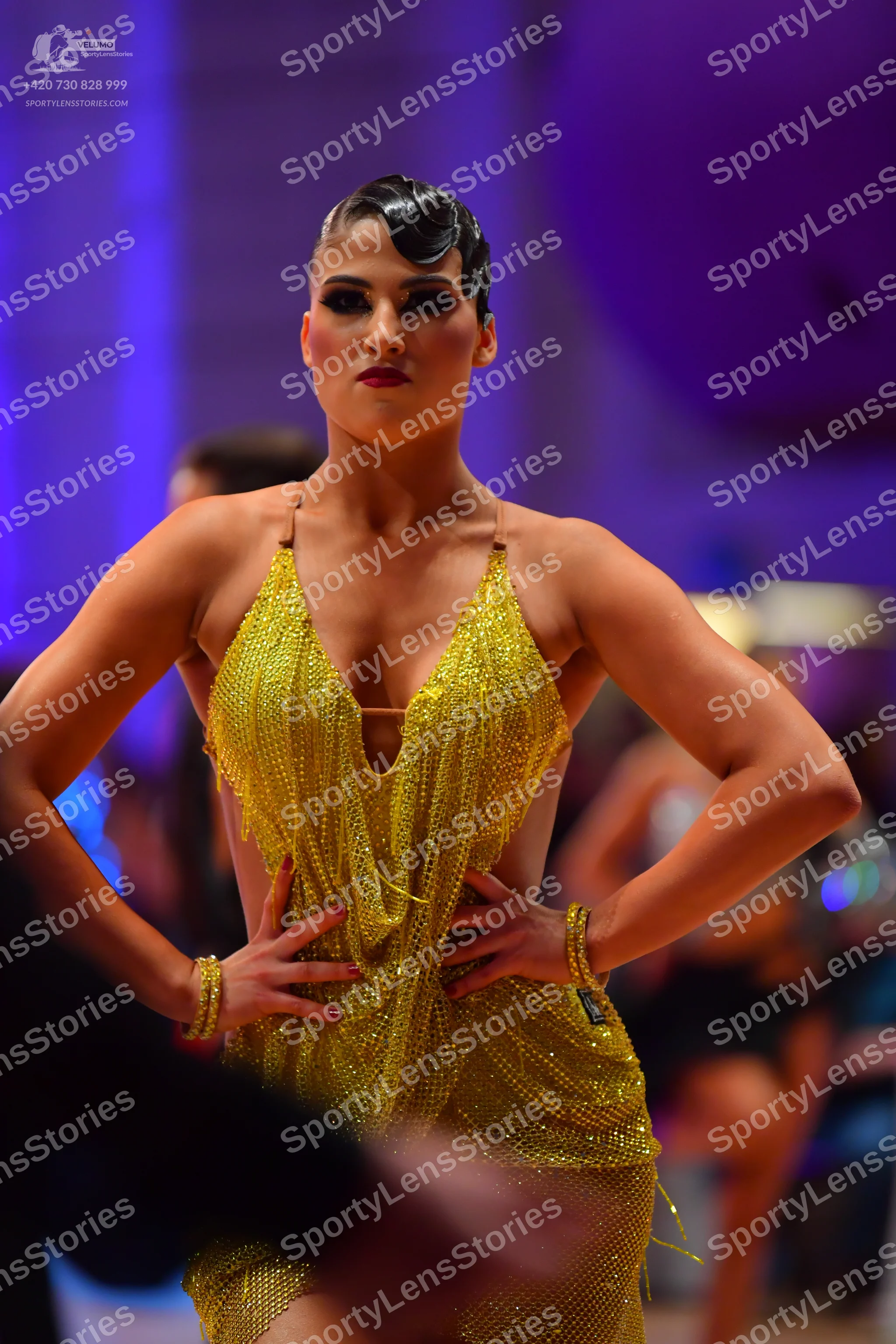 Dancesport competitor: Female dancer: gold sequined latin dress with thin straps and a deep V-neckline,