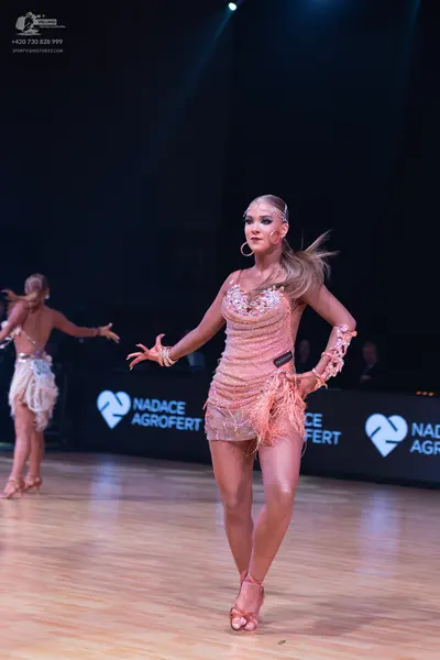 Dancesport competitor: Female dancer in foreground: peach-colored Latin dance dress with sequins and fr