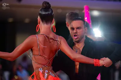 Dancesport competitor: Female dancer: orange Latin dress with thin sparkly straps and sequin embellishm