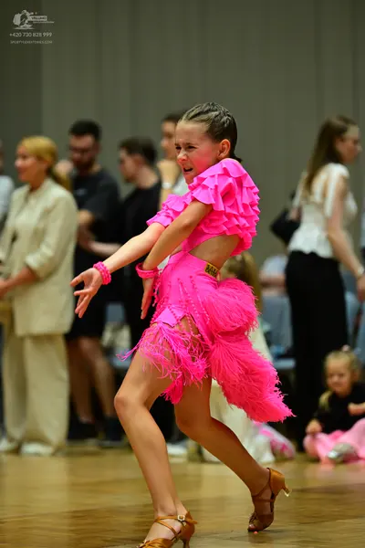 Dancesport competitor: Female dancer: bright pink Latin dance dress featuring layers of fringe and peta