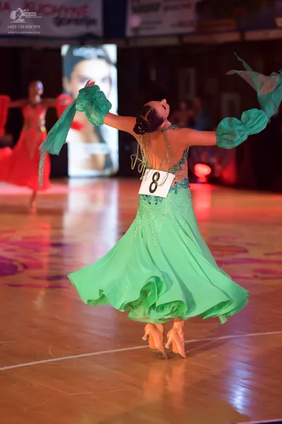 Dancesport competitor: Female dancer in foreground: mint green flowing ballroom dress with sequined bod