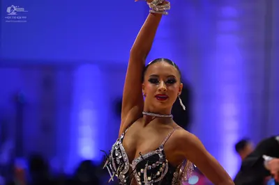 Dancesport competitor: Female dancer: black Latin dance costume heavily embellished with silver sequins