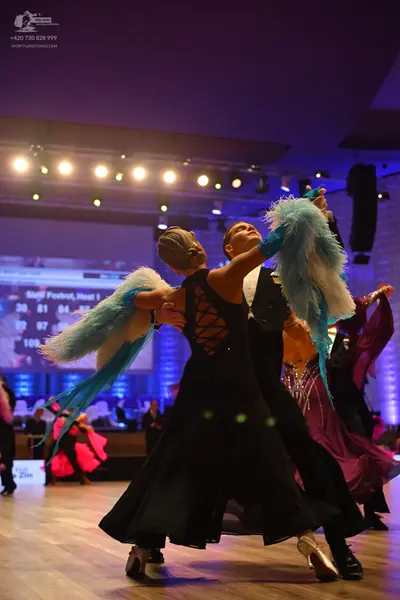 Dancesport competitor: Female dancer: black ballgown with a criss-cross lace-up back and a large flowin