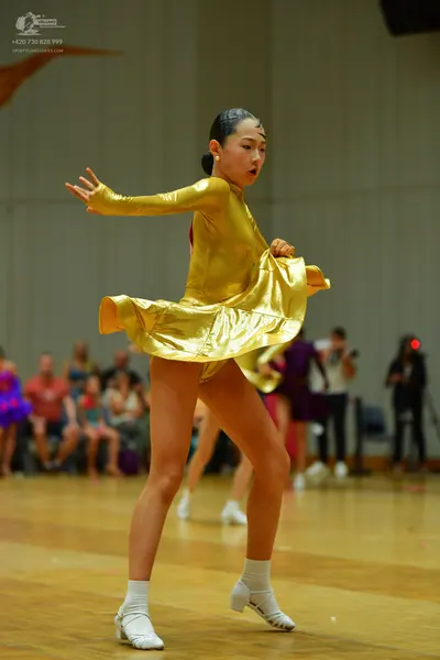 Dancesport competitor: Main female dancer: metallic gold long-sleeved latin dress