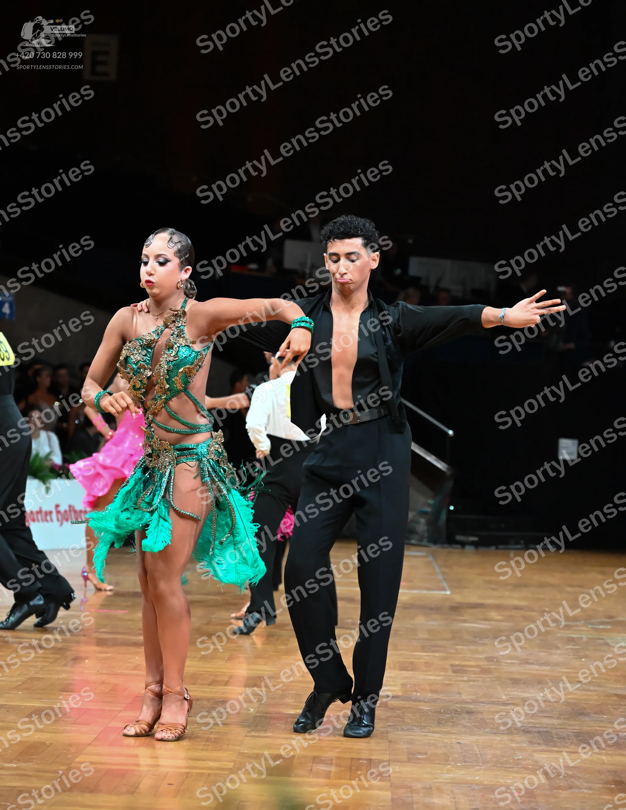 Dancesport competitor: Female dancer: teal and bright pink latin dance dress with sequins, lace, and fr