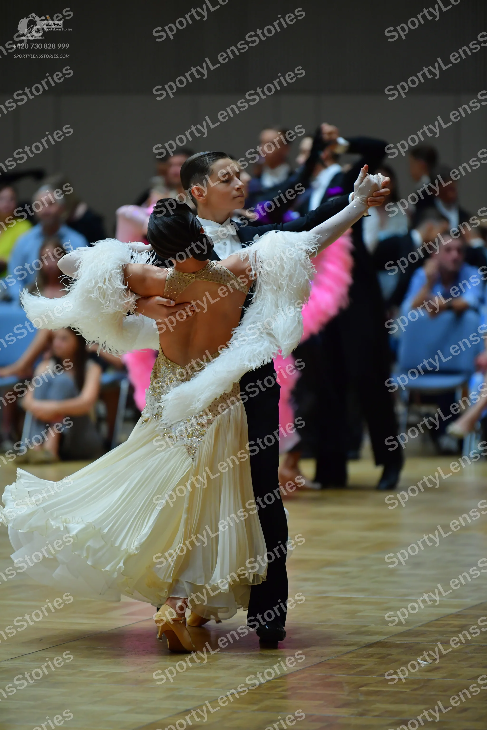 Dancesport competitor: Female dancer: white ballroom gown with a pleated skirt, a shimmering bodice, an