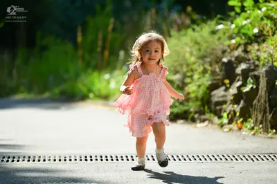 Dancesport competitor: The child is wearing a pink and white checkered, sleeveless, ruffled dress