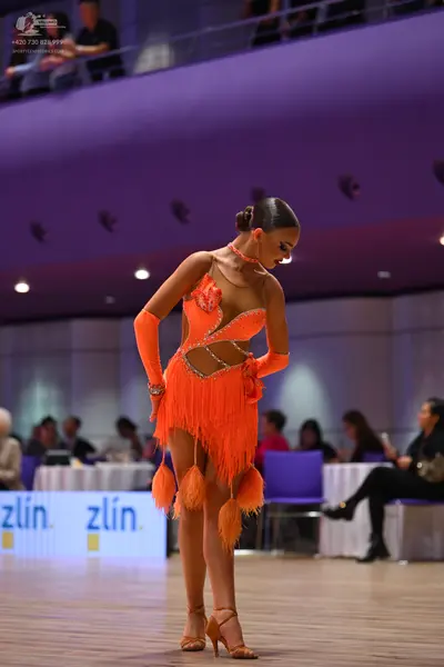 Dancesport competitor: Female dancer: bright orange Latin dance dress with fringe, cut-outs, and matchi