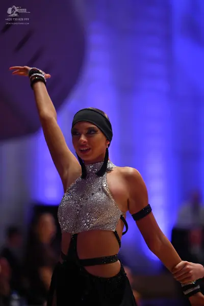 Dancesport competitor: Female dancer: silver sequined halter neck crop top with black straps, black hea