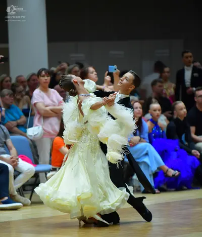 Dancesport competitor: Female dancer: cream-colored voluminous ballroom gown with many layers of ruffle
