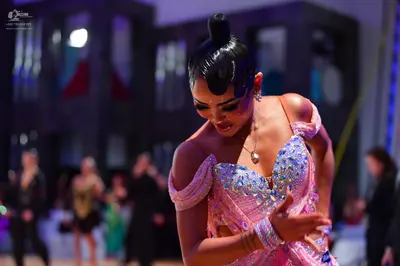 Dancesport competitor: Main female dancer: pink Latin dress heavily embellished with sequins and crysta