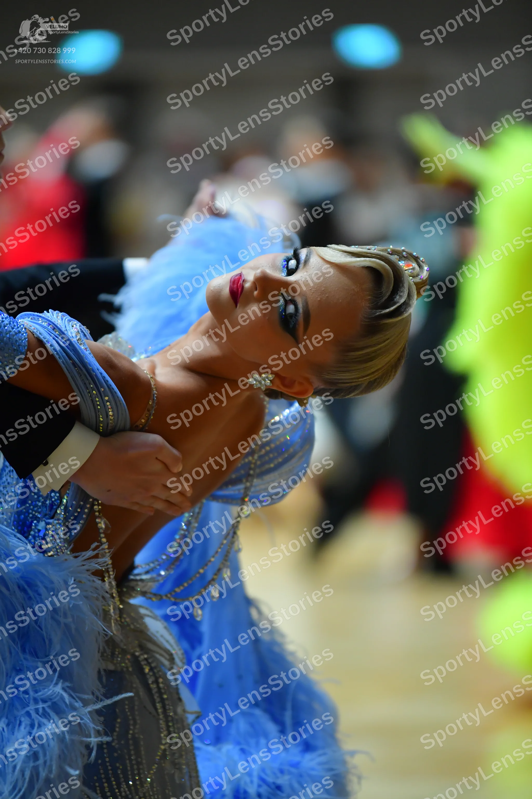 Dancesport competitor: Female dancer: light blue sequined latin dress with large blue feather accents a
