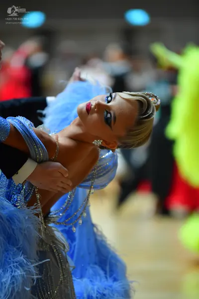 Dancesport competitor: Female dancer: light blue sequined latin dress with large blue feather accents a