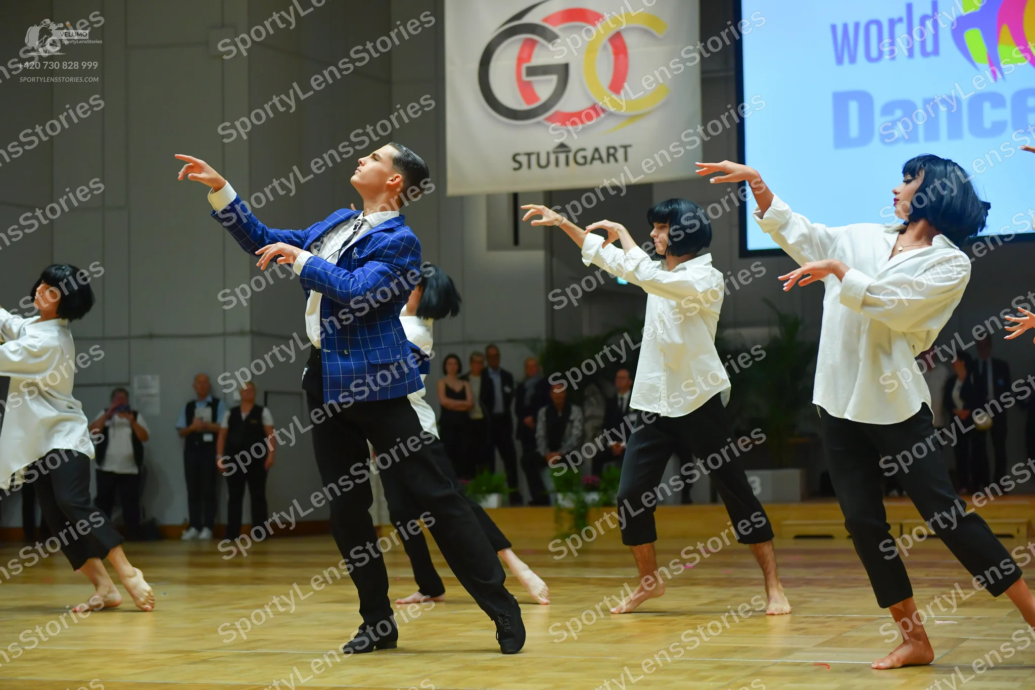 Dancesport competitor: Male dancer: blue checkered suit jacket, white shirt, black tie, and black trous