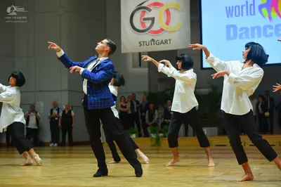 Dancesport competitor: Male dancer: blue checkered suit jacket, white shirt, black tie, and black trous