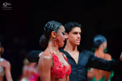 Dancesport competitor: Foreground female dancer: red lace/floral appliqué Latin top