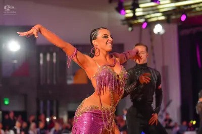 Dancesport competitor: Female dancer: pink/purple sequined Latin dance costume with long fringe and lar