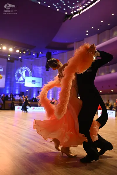 Dancesport competitor: Female dancer: peach ballroom gown with large, voluminous, fluffy/feathered trim