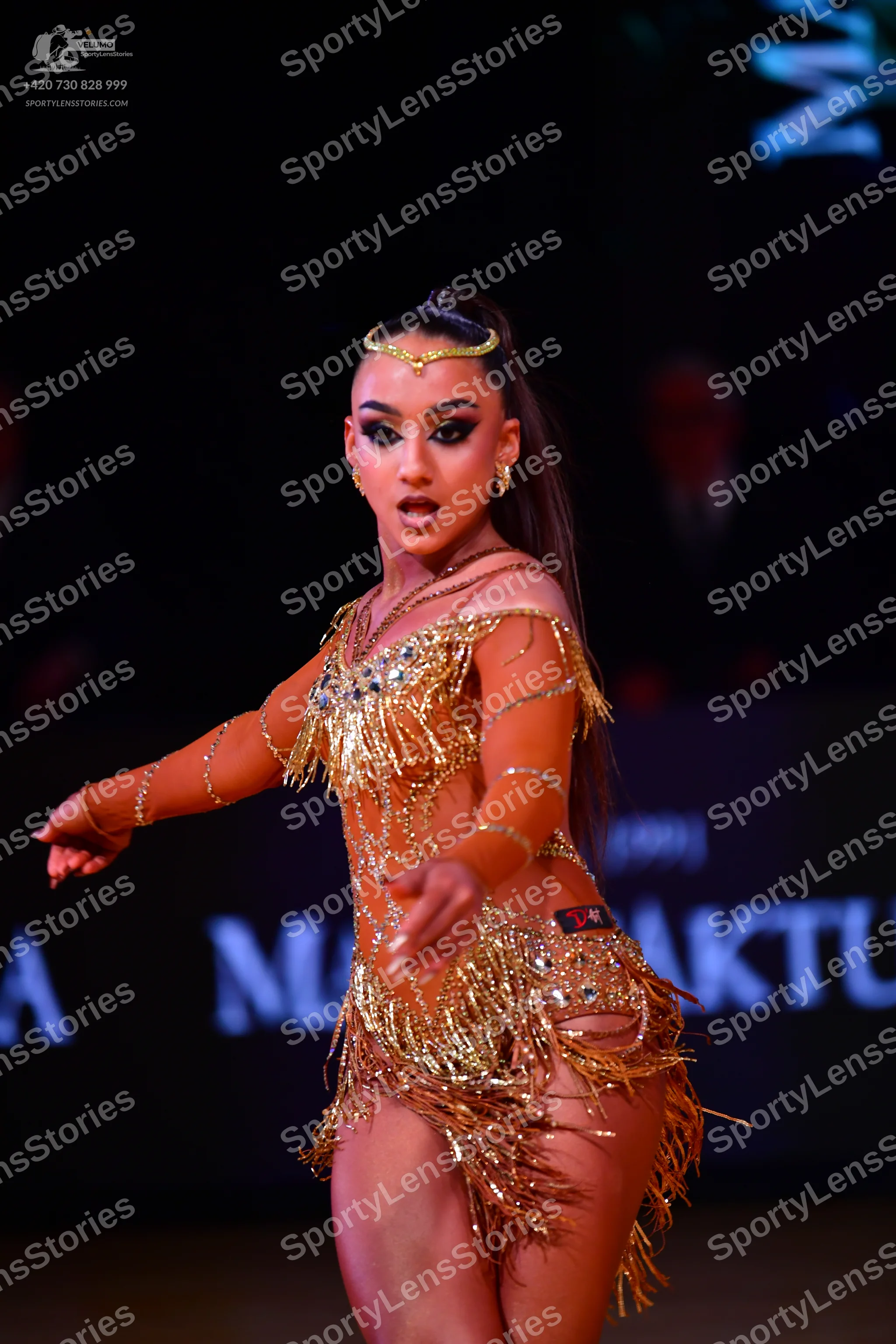 Dancesport competitor: Female dancer: gold latin dress with sequins, crystals, and long fringe on the s