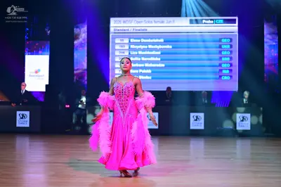 Dancesport competitor: Female dancer: bright pink ballroom dress with a sequined bodice and large pink 
