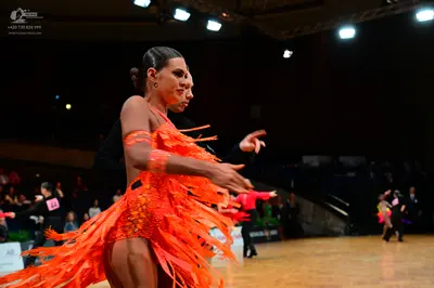 Dancesport competitor #148: Female dancer in foreground: orange latin dress with long fringe