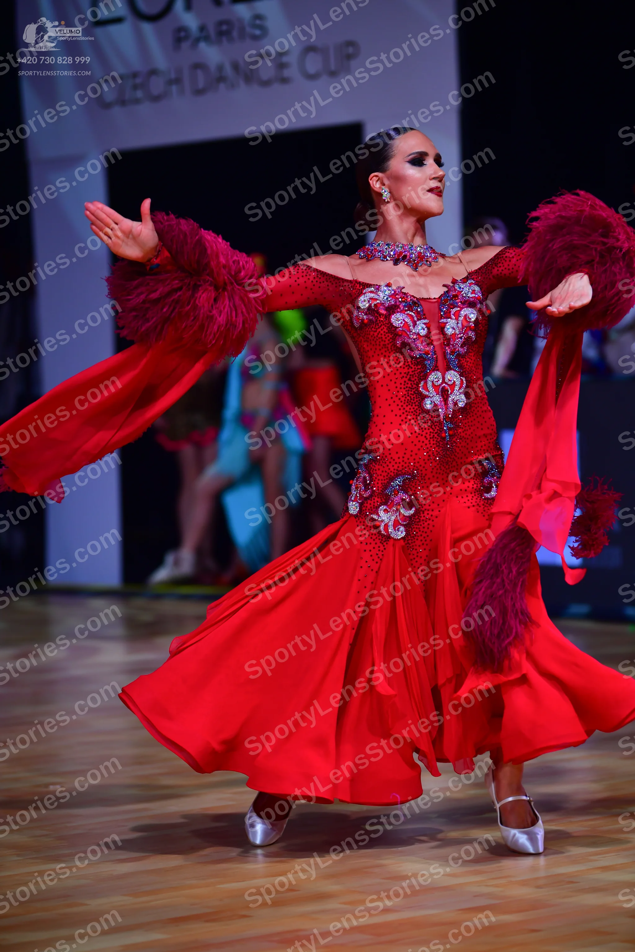 Dancesport competitor: Main female dancer: red Latin dress with a sequined and beaded bodice, long flow